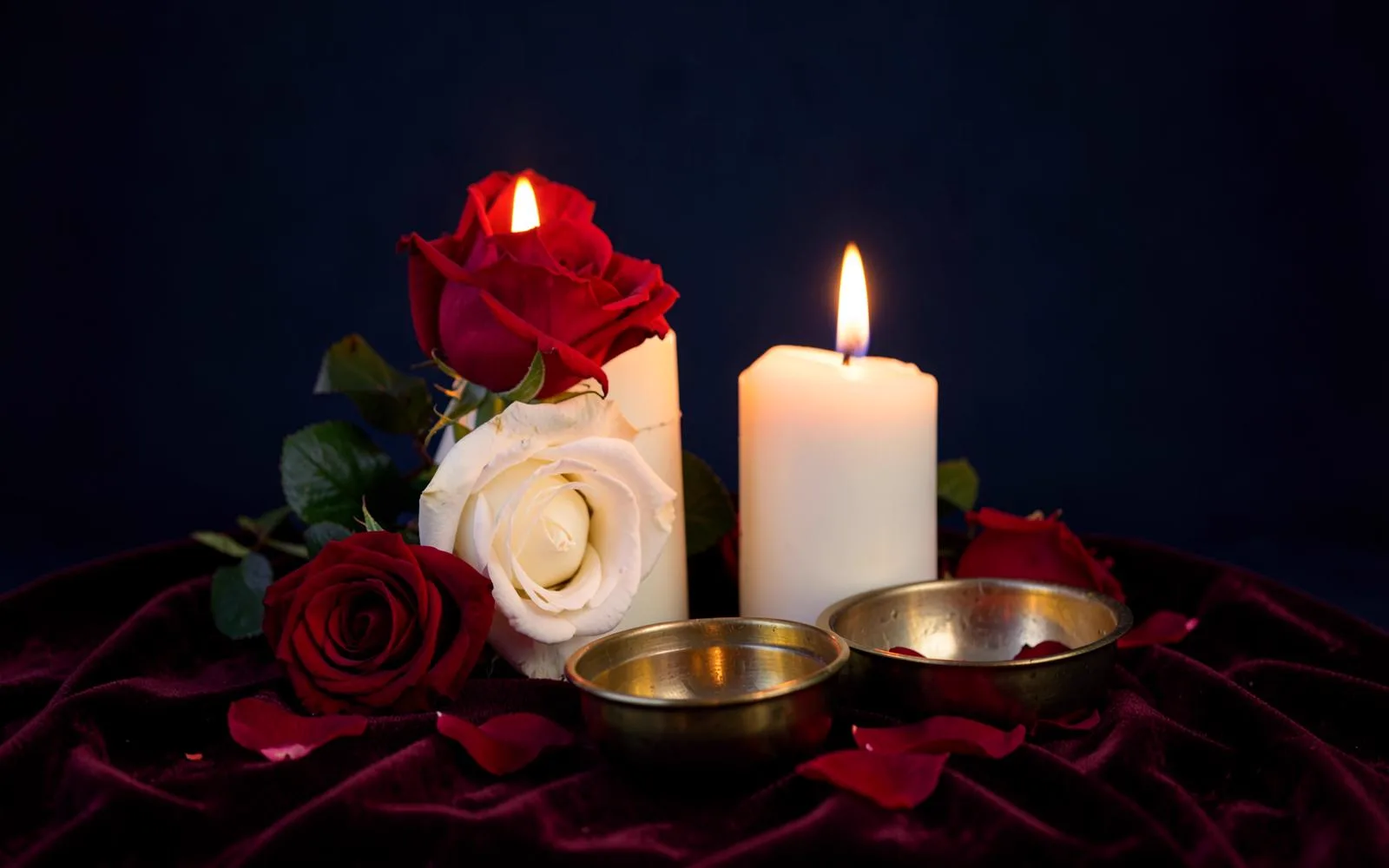 A candle burning beside dried roses and an open journal